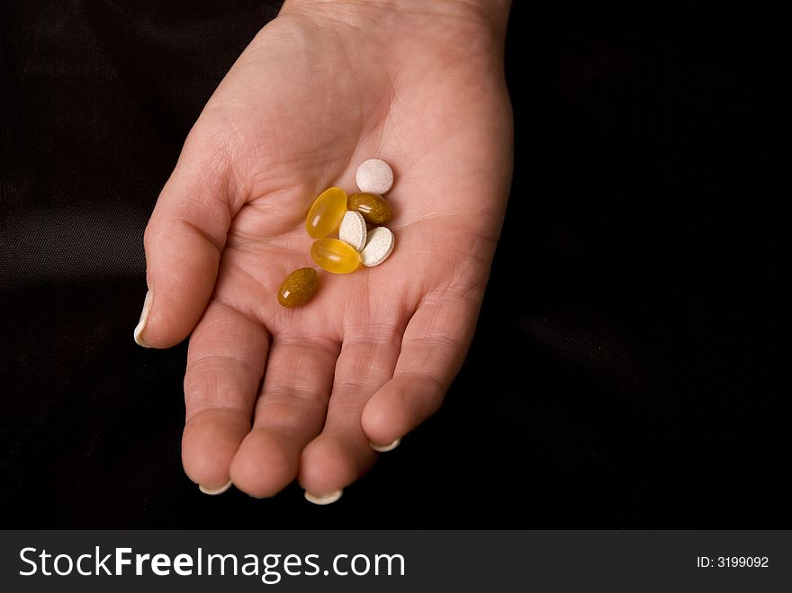 Hand holding pills and tablets on black background. Hand holding pills and tablets on black background