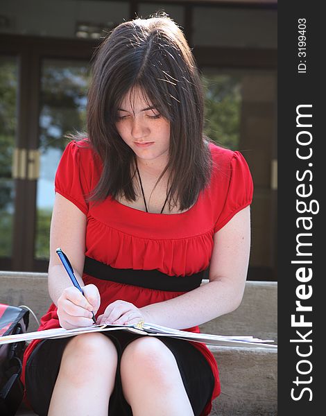 Beautiful 14 year old girl doing homework outside at school. Beautiful 14 year old girl doing homework outside at school.