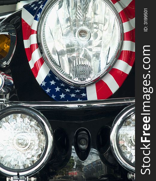 Detail of scooter with the pattern of the American flag wrapped around the headlight. Detail of scooter with the pattern of the American flag wrapped around the headlight.