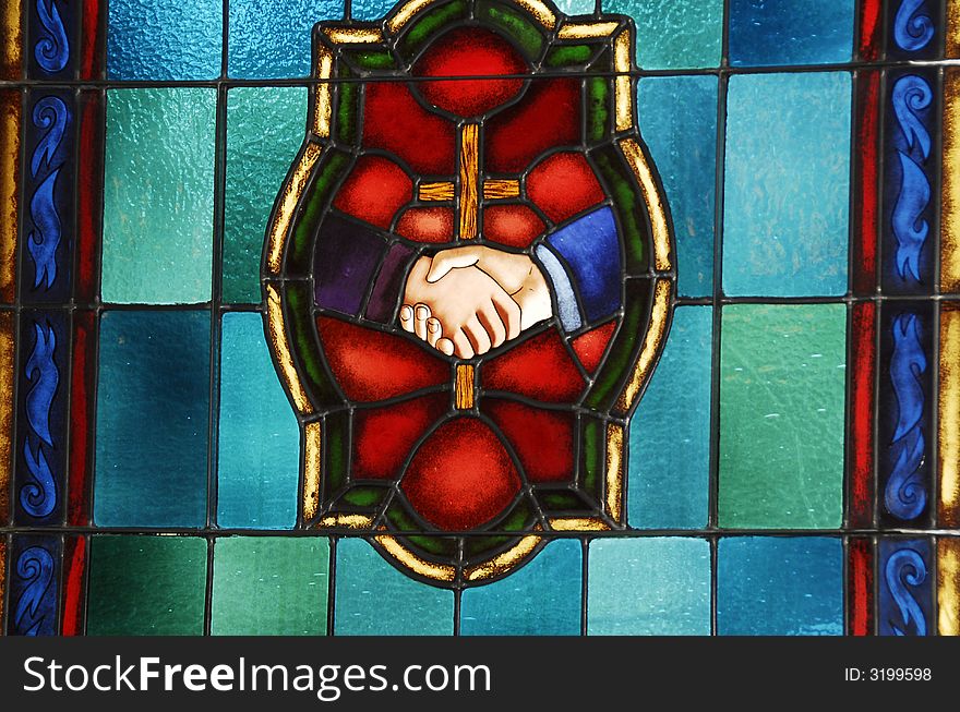 Stain glass window with a center cross and two hands