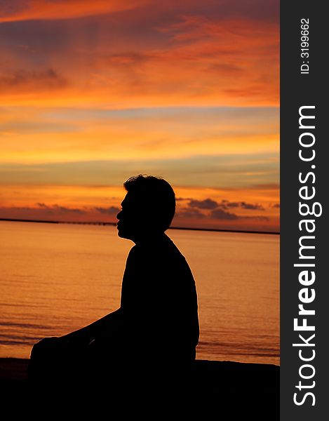 A man sitting by sea in the sunset in Langkawi, Malaysia. A man sitting by sea in the sunset in Langkawi, Malaysia.