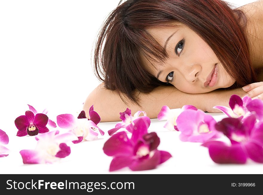 A young Asian woman lying on the floor with purple orchid flowers. A young Asian woman lying on the floor with purple orchid flowers