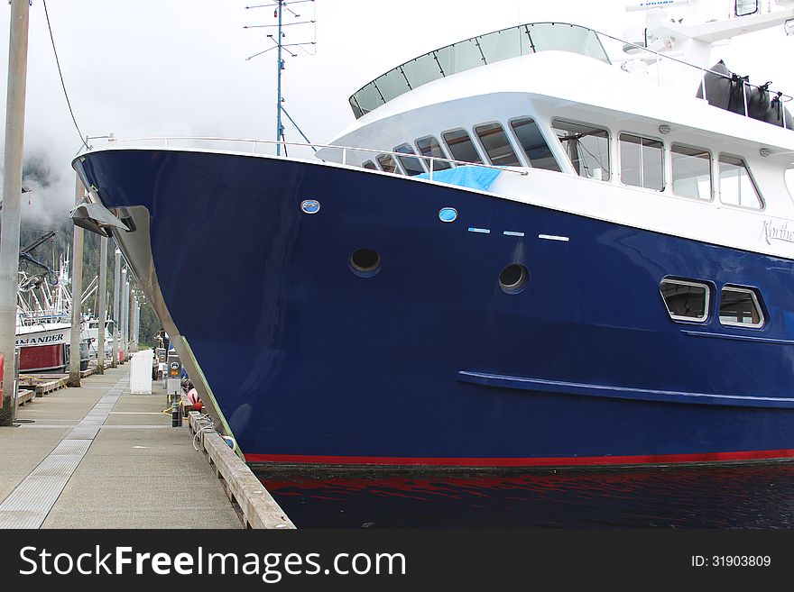 A large boat with blue hull for taking tourists on expeditions sits tied up in Petersburg, Alaska harbor. A large boat with blue hull for taking tourists on expeditions sits tied up in Petersburg, Alaska harbor.