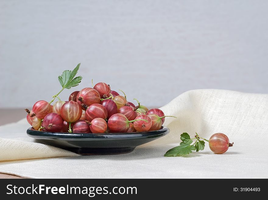 Ceramic cup with fresh gooseberries on a light background