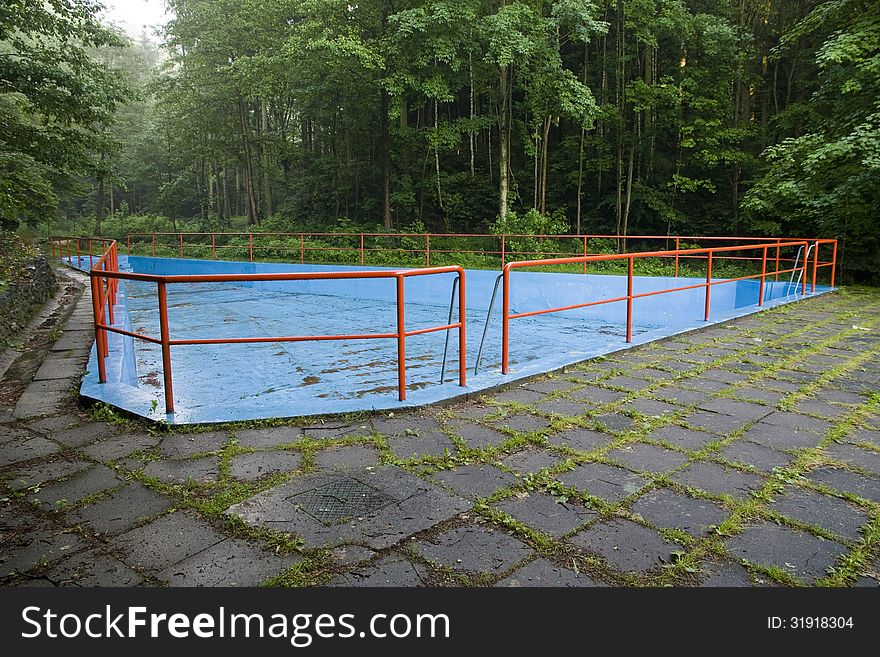 Drained pool blue with red railings, swimming pool in the middle of the forest