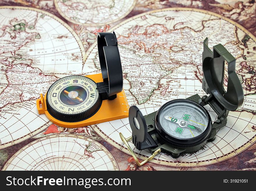 Two compass lie on the background of the map of the world. Two compass lie on the background of the map of the world