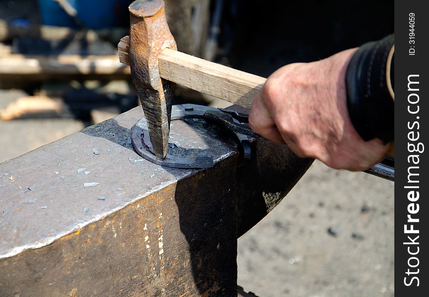 The smith making forges a horseshoe on an anvil