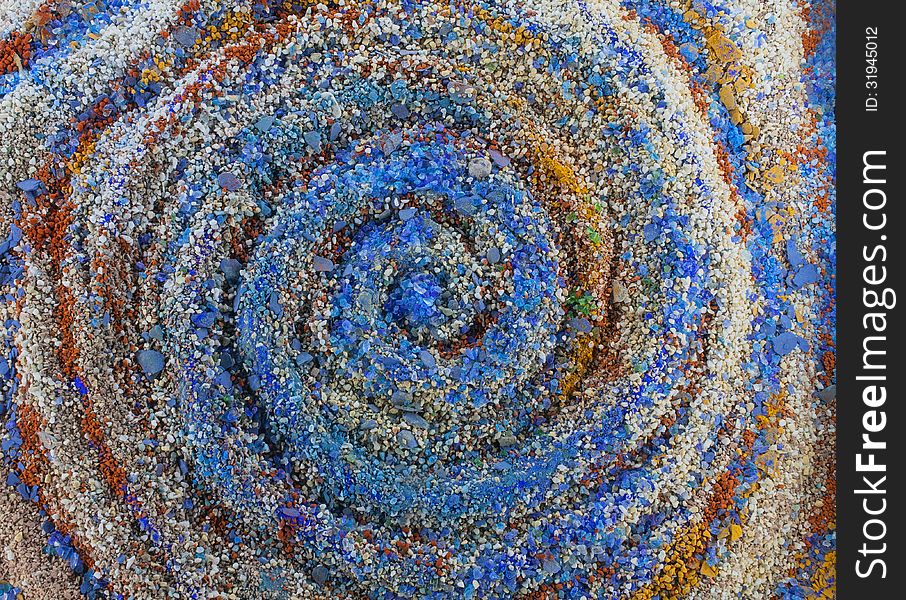 Close up on an abstract whirpool composition made by multicolored sand