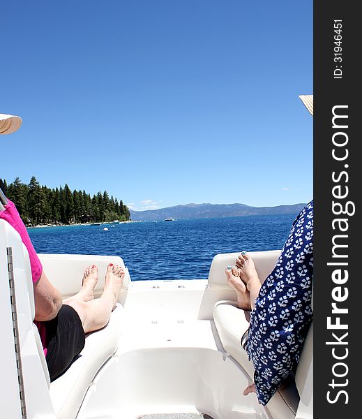 Two women relaxing on a boat on a blue lake. Two women relaxing on a boat on a blue lake