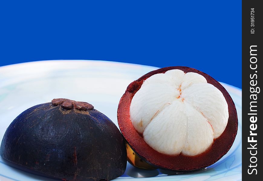 A mangosteen is half-cut to show its white flesh.