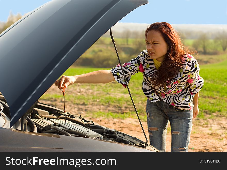 Young woman bent over car engine