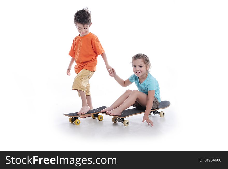 Photography of preschool boy and girl ridding skate board in a studio on white background. Photography of preschool boy and girl ridding skate board in a studio on white background