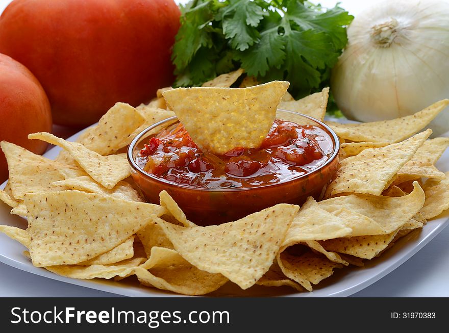 A Plate of chips and salsa with onion, cilantro and tomatoes