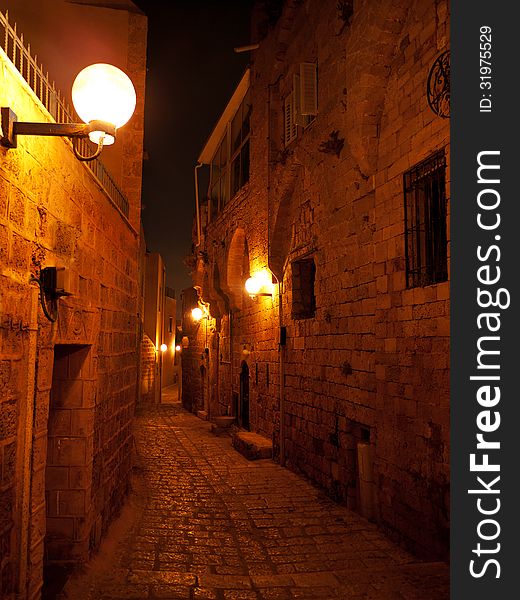 Narrow stone paved medieval street at night