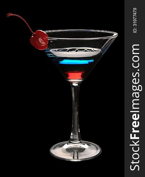 Tri-color cocktail martini with a cherry on a black background