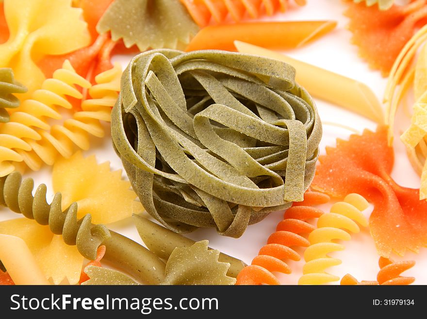 Green tagliatelle paglia e fieno on the backgroun of different pastas. Green tagliatelle paglia e fieno on the backgroun of different pastas.