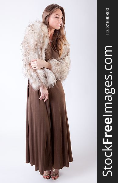 An image of a gorgeous model in a long brown dress and fur coat. An image of a gorgeous model in a long brown dress and fur coat