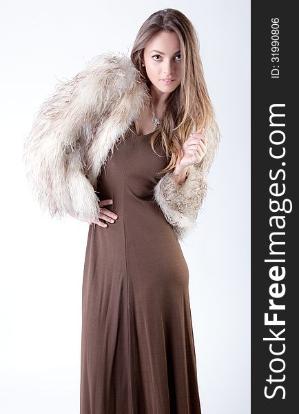 An image of a model in a brown dress and fur coat. An image of a model in a brown dress and fur coat