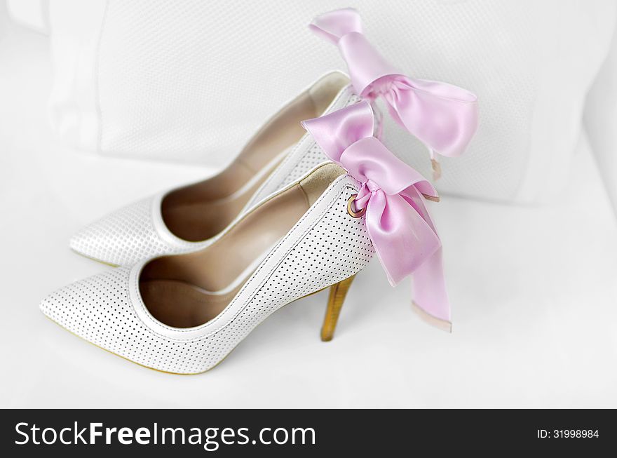 White elegant woman shoes with a pink ribbon. White elegant woman shoes with a pink ribbon.