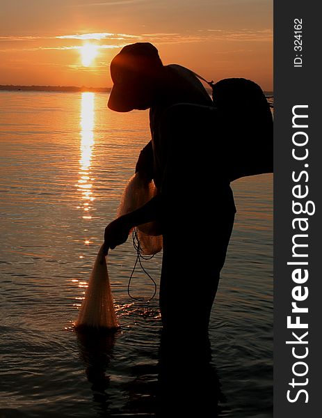 Fisherman netting fish during sunset