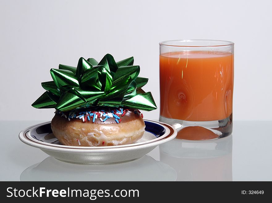 A doughnut with a bow on top is served with juice for Christmas breakfast
