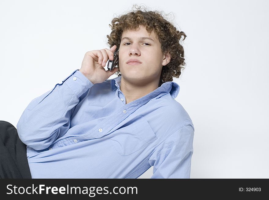 (Boy in relaxed office attire) Boy lying down, leaning up on one arm talking on a cellphone. (Boy in relaxed office attire) Boy lying down, leaning up on one arm talking on a cellphone