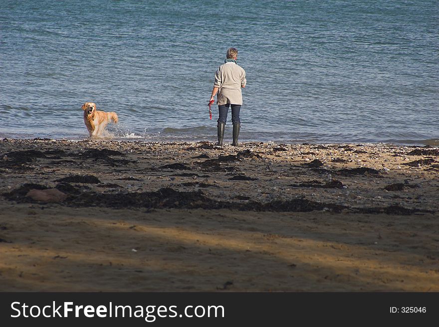 Woman & dog on playing on the seashore