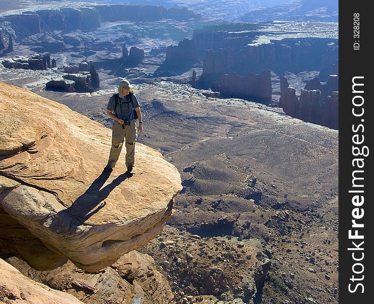 Hiker admires the vista from a risky perch. Hiker admires the vista from a risky perch