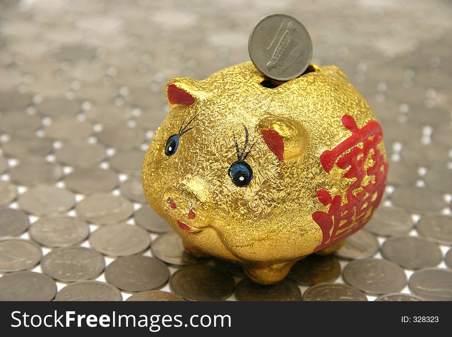 Piggy bank with Chinese prosperity symbol, standing on a floor of coins