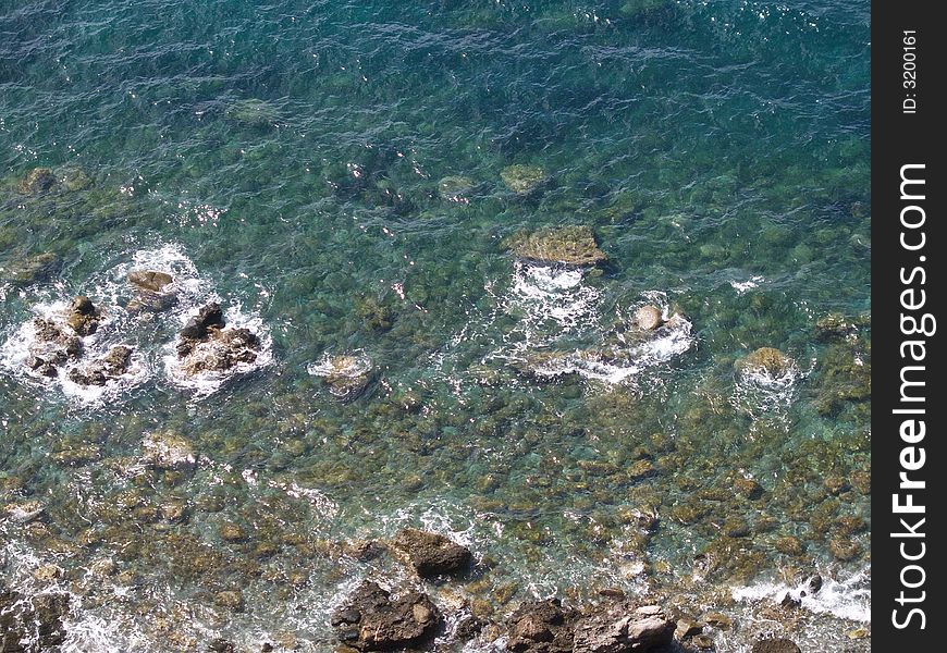 Sea landscape, trasparent and blue water, and stones