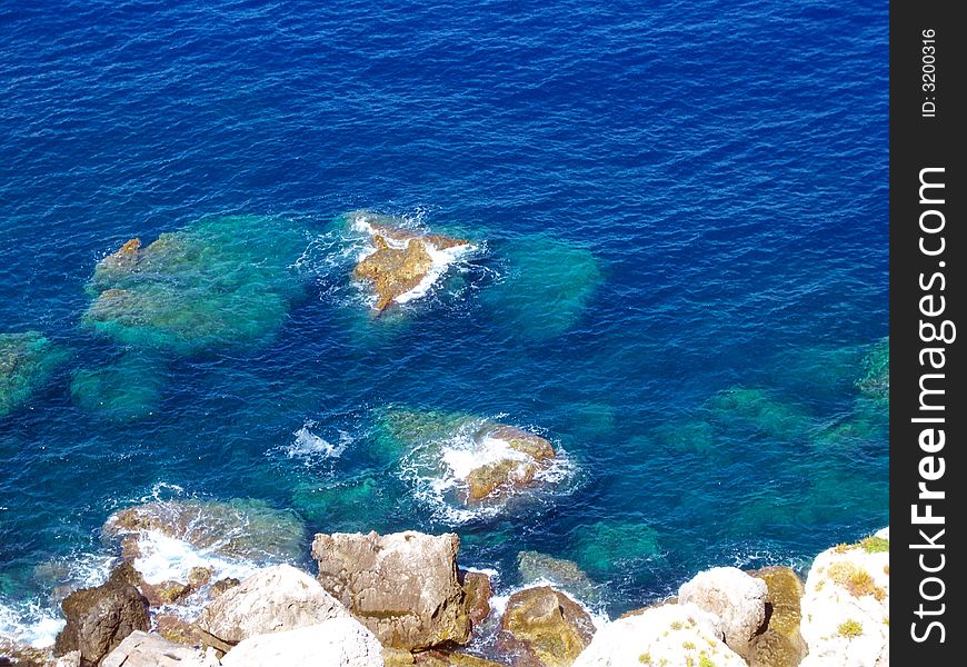 Sea landscape, trasparent and blue water, and stones