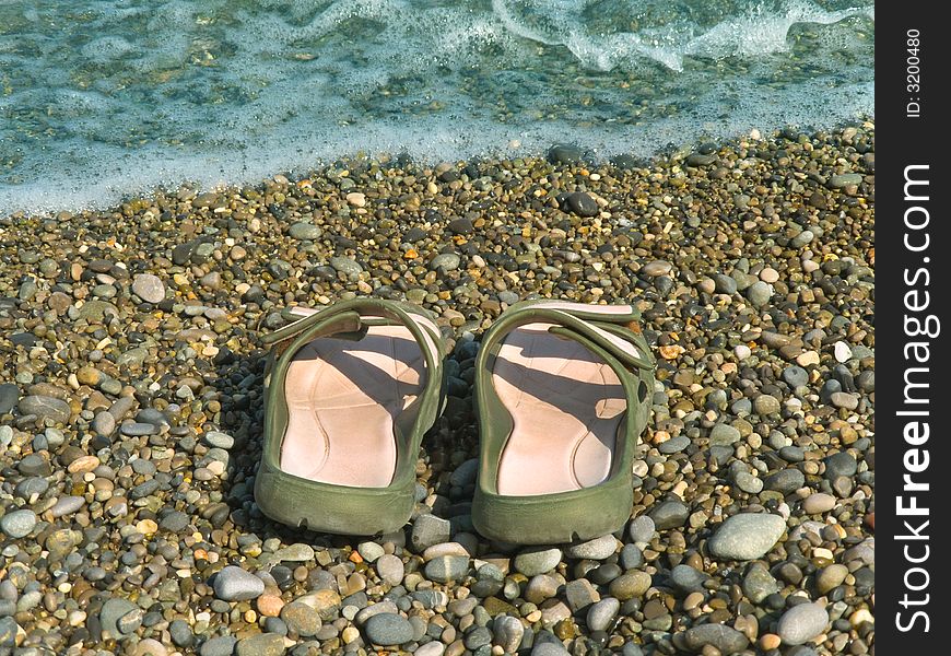 Pair of slipper on beach and wave