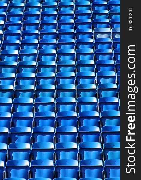 Rows of empty blue stadium seats. Rows of empty blue stadium seats