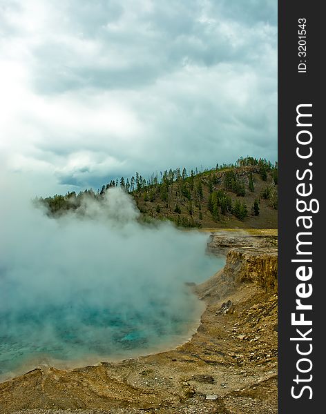 A picture of steam comming up from a geyser basin in Yellowstone National Park