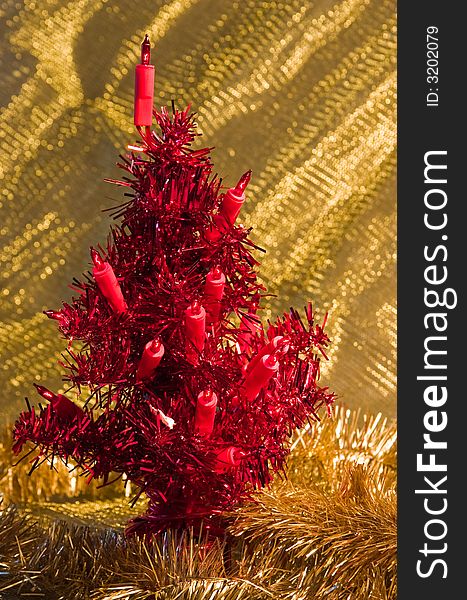 Artificial red christmas tree on a golden background
