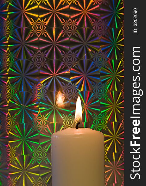 Burning candle on a reflective iridescent background. Burning candle on a reflective iridescent background