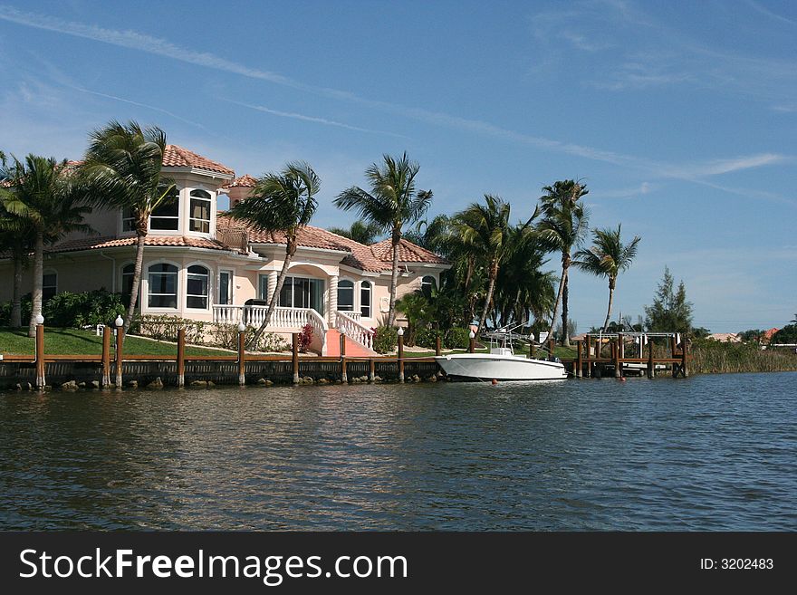 Photo of  a large boat, docked in front of a tropical home. Photo of  a large boat, docked in front of a tropical home