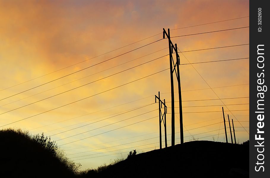 Beautiful soft sunset as backdrop for high voltage power lines on grassy hill. Beautiful soft sunset as backdrop for high voltage power lines on grassy hill