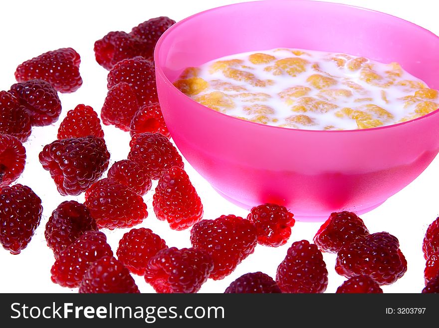 Milk with cornflakes inside pink bowl, raspberries around isolated on white