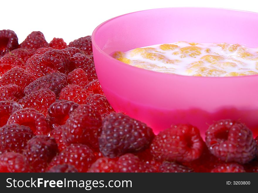 Milk with cornflakes inside pink bowl, raspberries around isolated on white