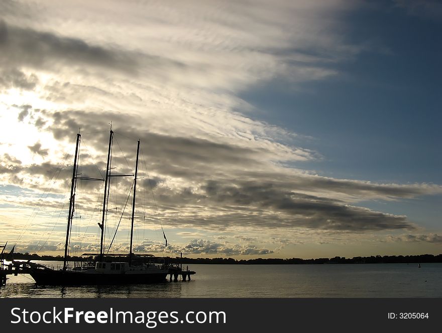 A sailing boat docked at the harbour in the sunrise. A sailing boat docked at the harbour in the sunrise