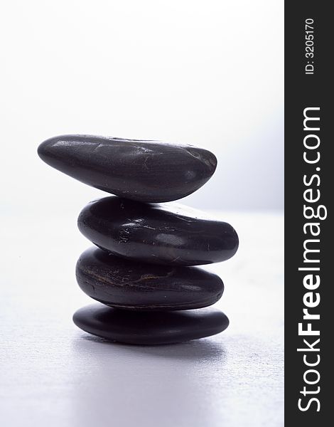 Four stapled, round, smooth black stones. Zen-Style. White background. Reassuring. Four stapled, round, smooth black stones. Zen-Style. White background. Reassuring.