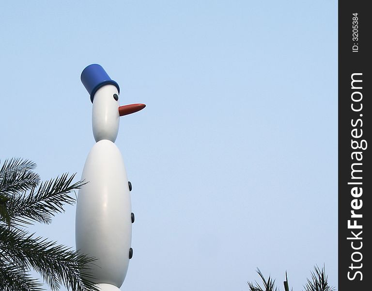 Ornamental snowman amidst palm fronds in a cloudless blue sky. Appropriate for a tropical Christmas card or tropical vacation theme. Ornamental snowman amidst palm fronds in a cloudless blue sky. Appropriate for a tropical Christmas card or tropical vacation theme.