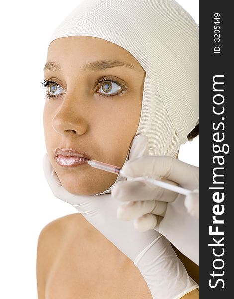 Young, beautiful woman with bandage on head. Somebody is injecting something in her's lips. Side view, white background. Young, beautiful woman with bandage on head. Somebody is injecting something in her's lips. Side view, white background
