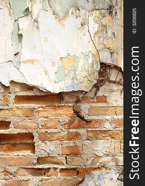 Old cracked wall with brick exposed and peeled paint