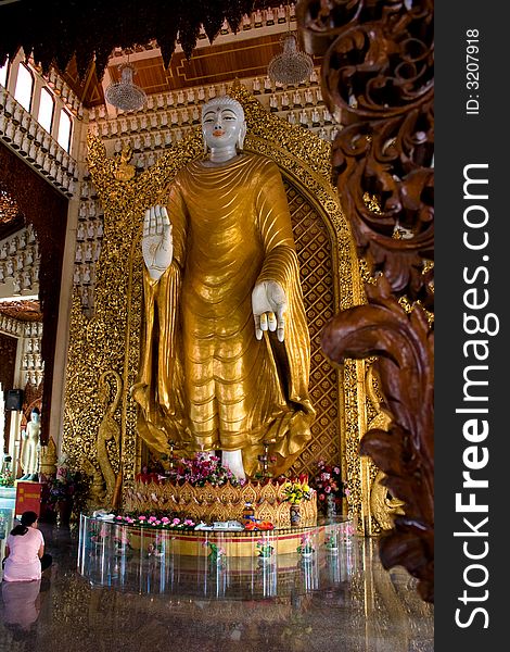 A golden Buddha statue with wood carvings in the foreground