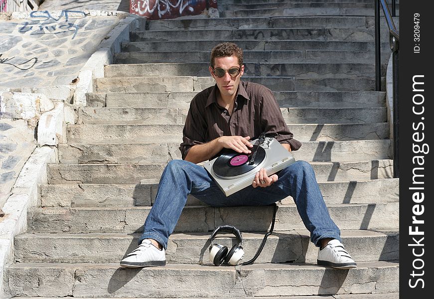 Dj sits on steps outside with turntable. Dj sits on steps outside with turntable