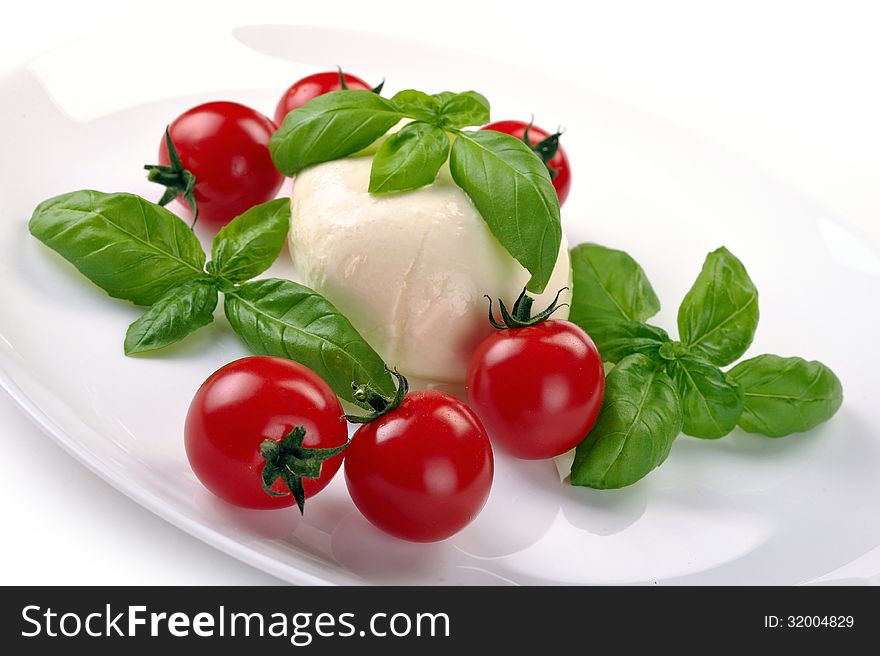 Mozzarella cherry tomatoes basil on a white plate