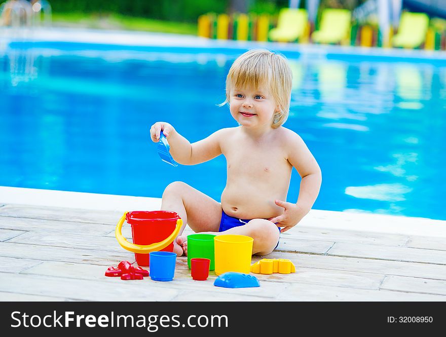 Positive kid playing with his toys by the swimming pool. Positive kid playing with his toys by the swimming pool