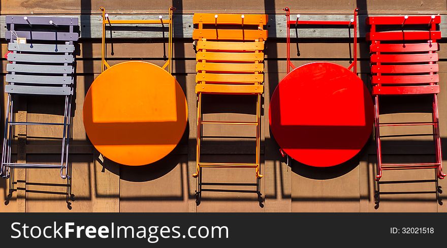 Different colored chairs and tables hanging on the wall.